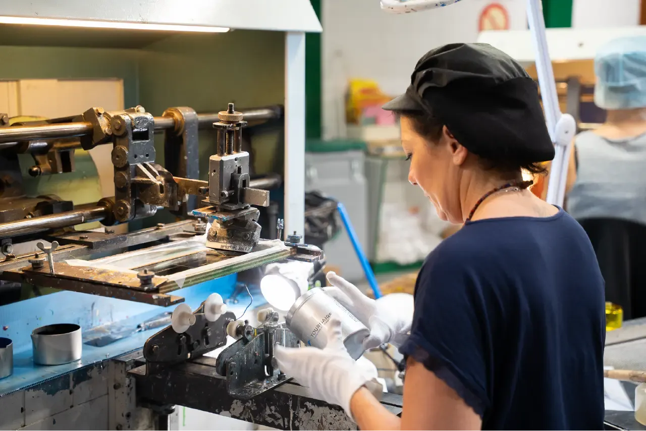 Operator at the Tournaire Group's Leaders workshop screen printing a customized aluminum container.